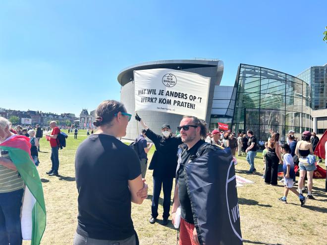 Techwerkers in gesprek met een spandoek in de achtergrond